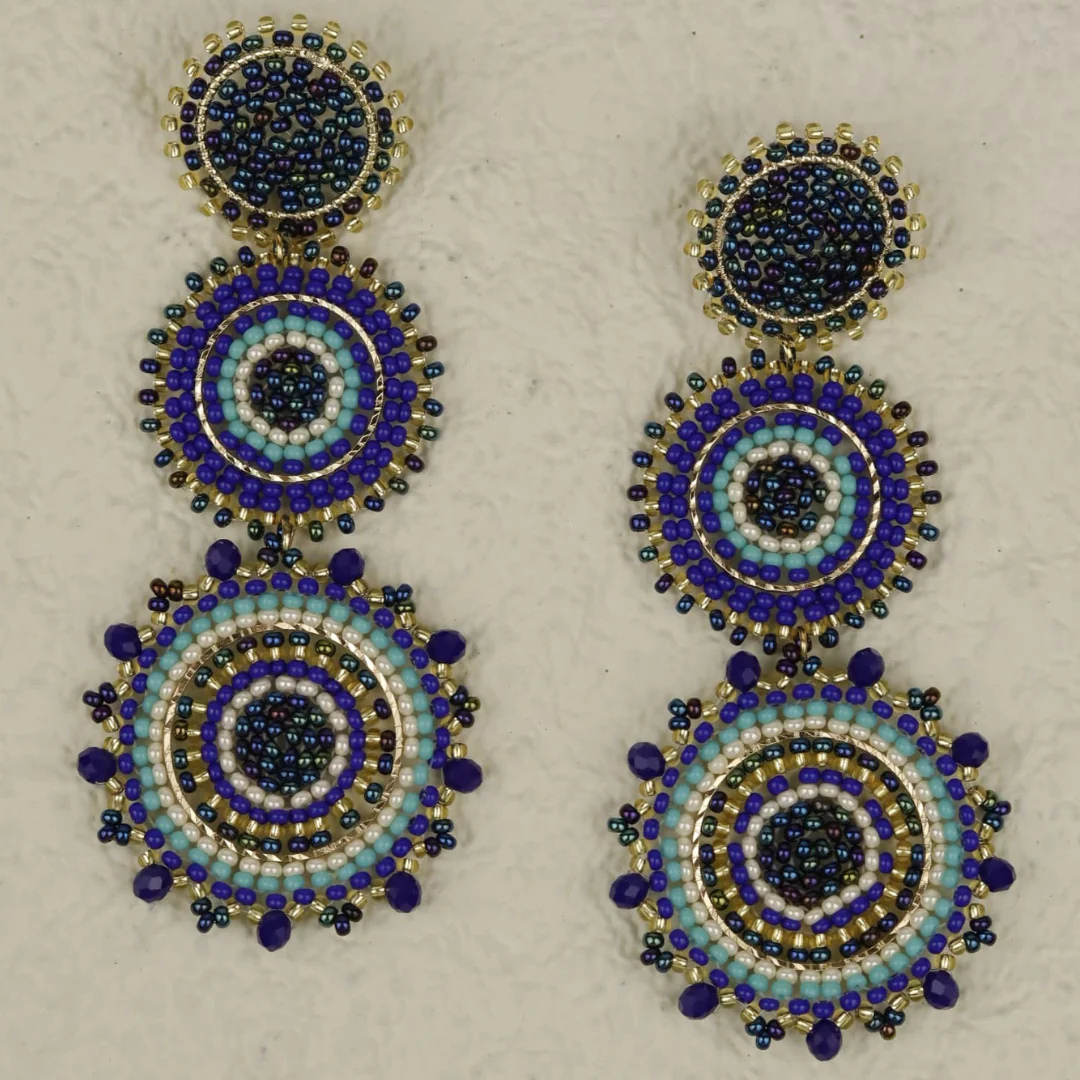 Pair of beaded earrings with blue and gold design on a light background