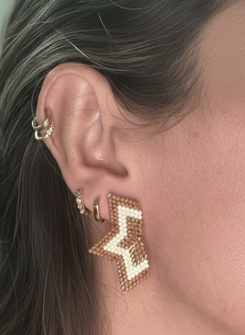 Close-up of a person wearing gold earrings with a neutral background