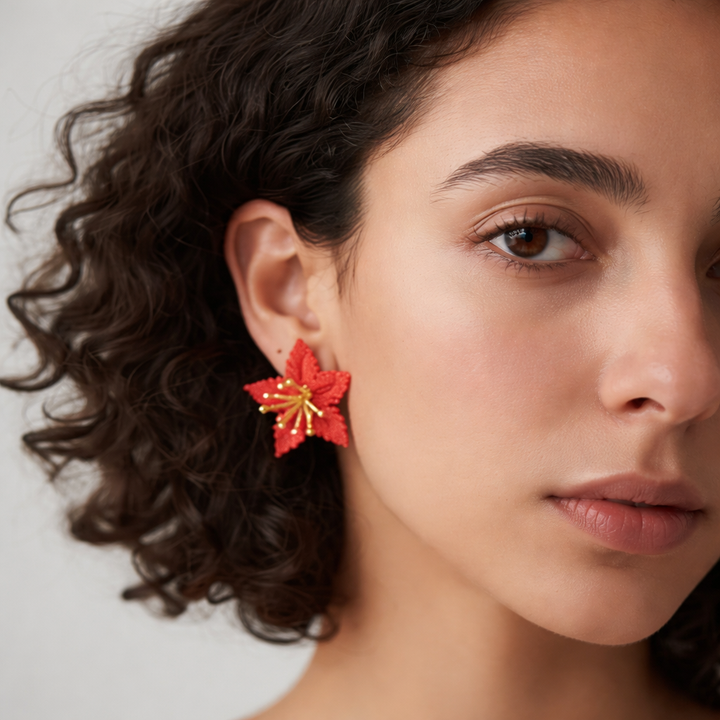 Close-up of a woman wearing a red floral earring against a neutral background